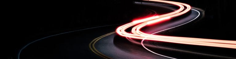 Long exposure image taken of a car driving down the road at night